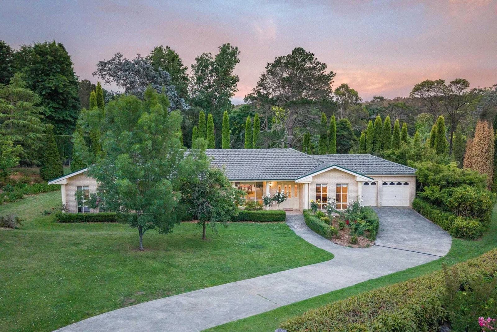 10 Copplestone Lane, Bowral viewed at dusk across the front lawn and curved driveway